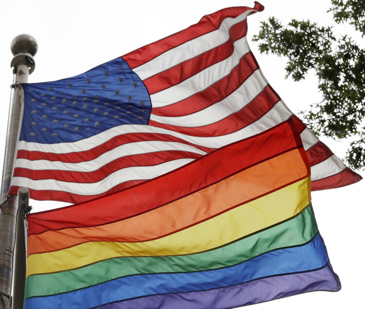 The Rainbow Flag flies beneath the American flag at the Stonewall National Monument, Wednesday, Oct. 11, 2017, in New York. The Rainbow Flag, an international symbol of LGBT liberation and pride, was flown for the first time at the monument. (AP Photo/Mark Lennihan)
